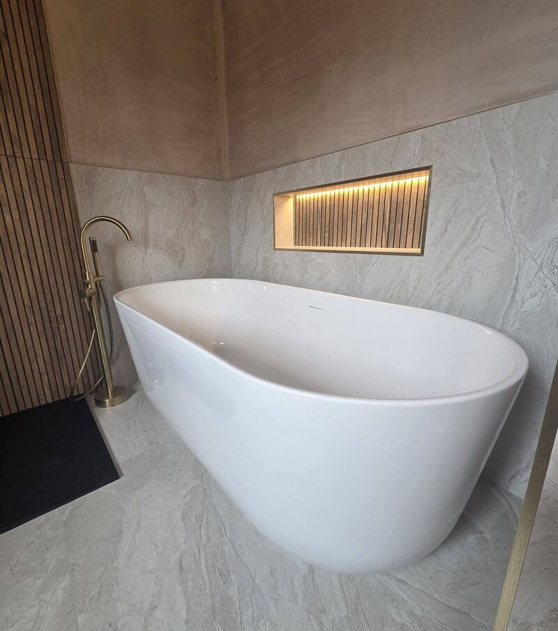 Freestanding bath with brass floor tap and a lit wall niche