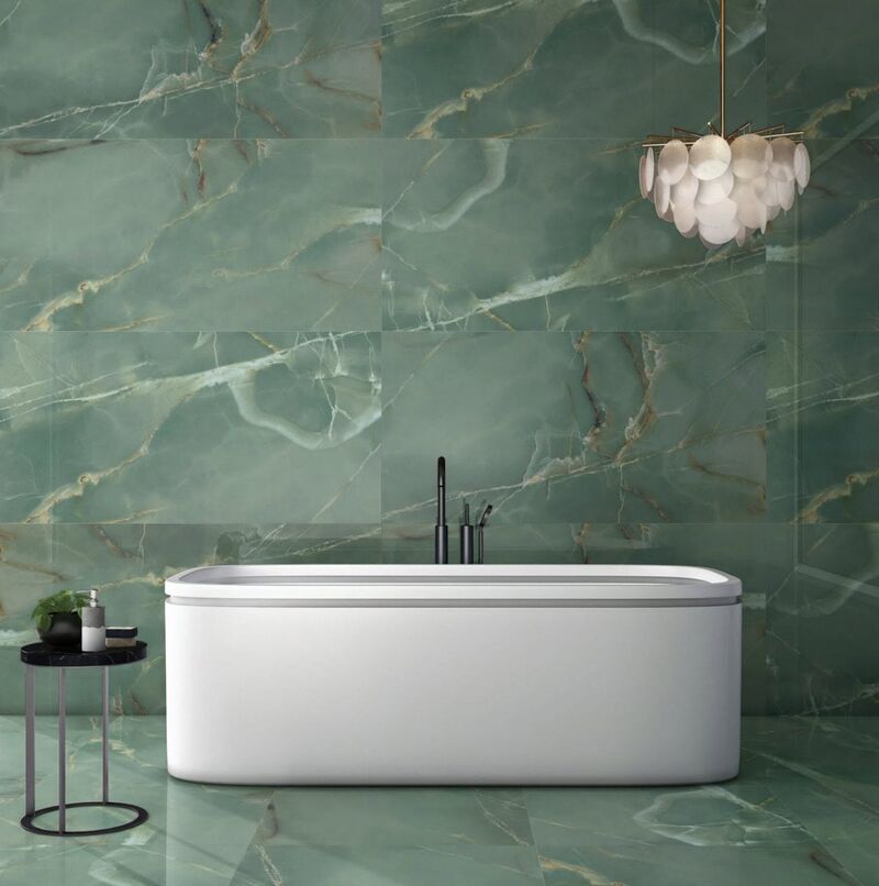 Freestanding bath against green onyx-effect tiled walls